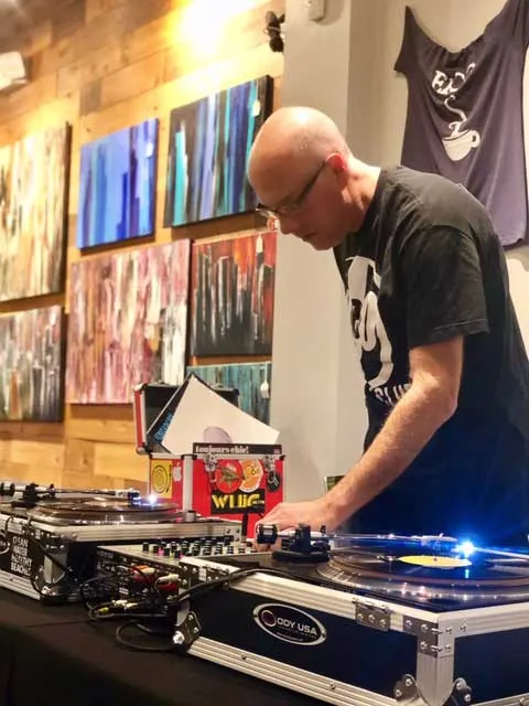 Kris Koch spinning vinyl at a DJ booth