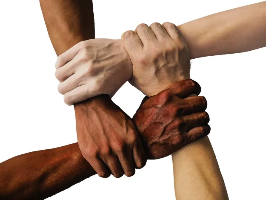 Four hands of different skin tones clasped together